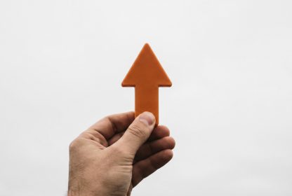 Mão segurando uma seta apontando para cima, representando crescimento e evolução no marketing digital em 2026.